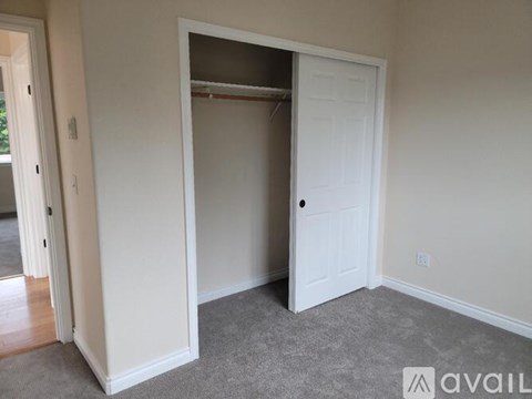 A room with a white door and a carpeted floor.