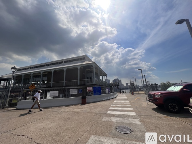 A man is walking across a crosswalk in front of a building with a cloudy sky above.