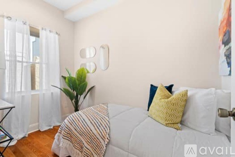 A bedroom with a bed, pillows, and a plant.