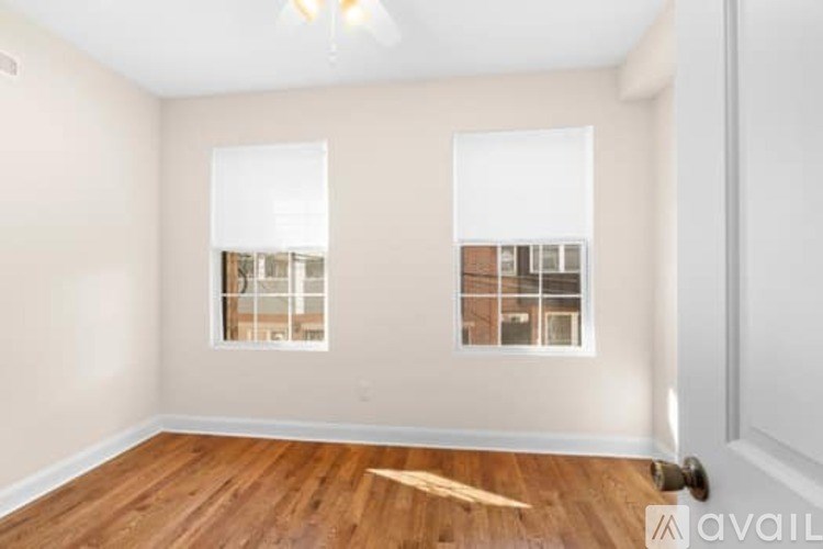 A room with wooden floors and two windows.