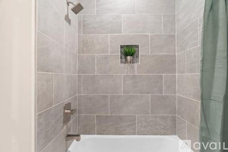 A bathroom with grey tiles and a small plant in a pot.