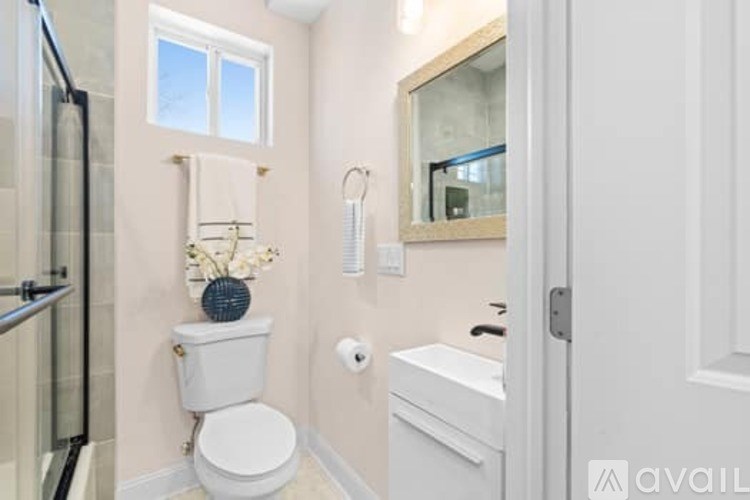 A white toilet sits next to a white sink in a bathroom.