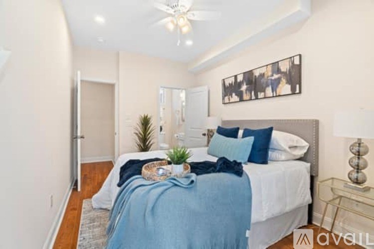 A bedroom with a bed covered in a blue blanket and a ceiling fan above it.