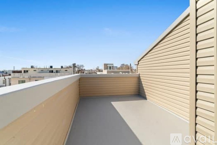 A rooftop patio with a wooden railing and a grey floor.