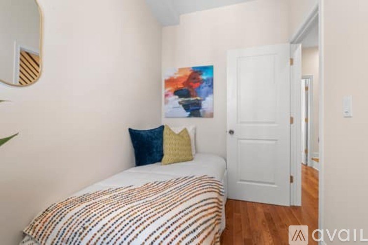 A bedroom with a bed, pillows, and a painting on the wall.