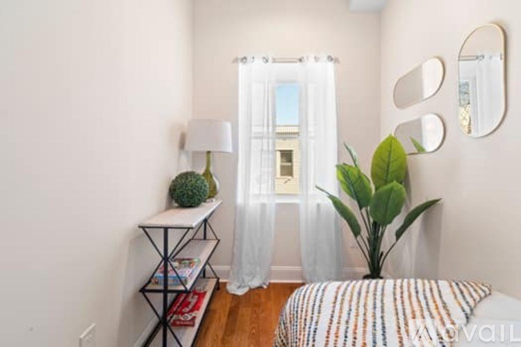 A bedroom with a bed, a plant, a lamp, and a mirror on the wall.