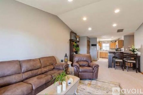 A living room with a brown couch and a brown leather chair.