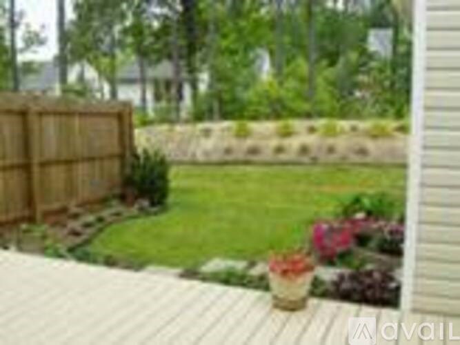 A wooden deck overlooks a garden with a fence and a wall.