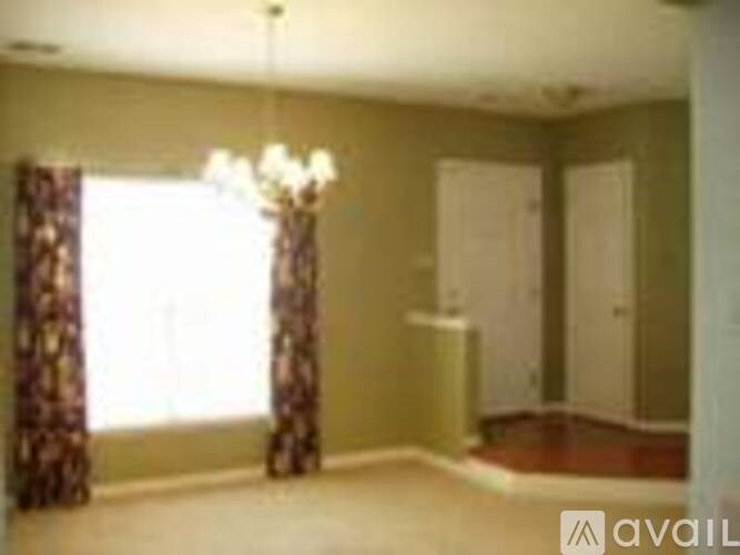 A room with a chandelier, two doors, and a window with curtains.