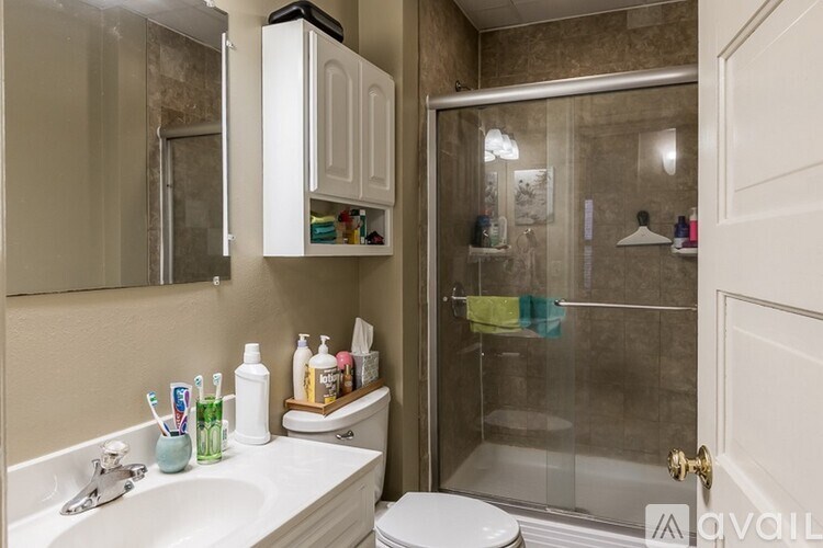 A bathroom with a white sink, toilet, and a glass shower door.