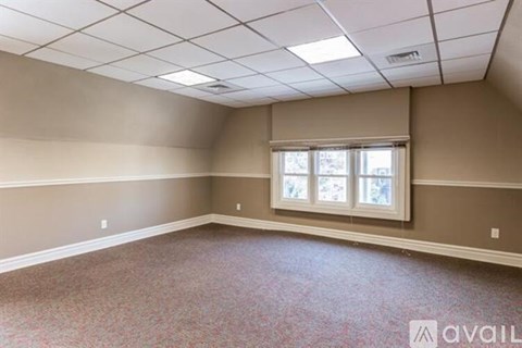 A spacious room with a window and carpeted floor.