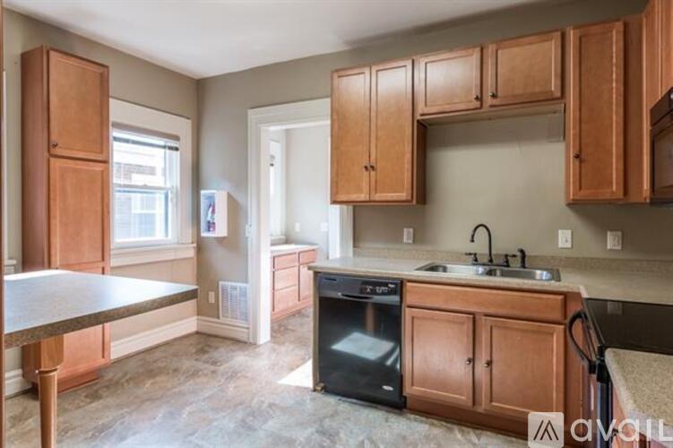 A kitchen with brown cabinets and a black dishwasher.