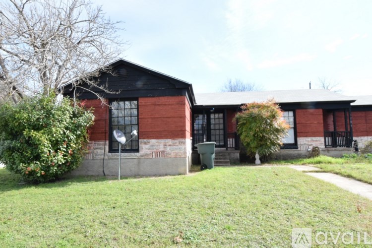 A red brick house with a green trash can in front.