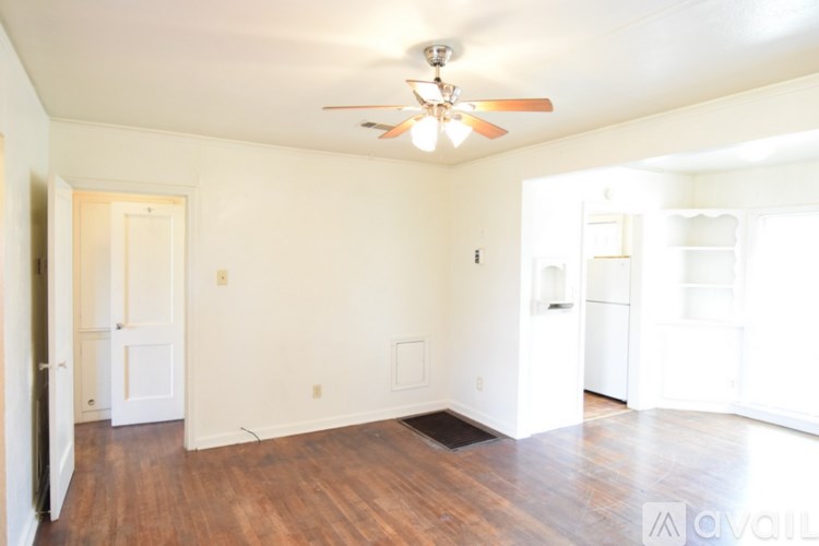 A room with a ceiling fan and wooden floors.