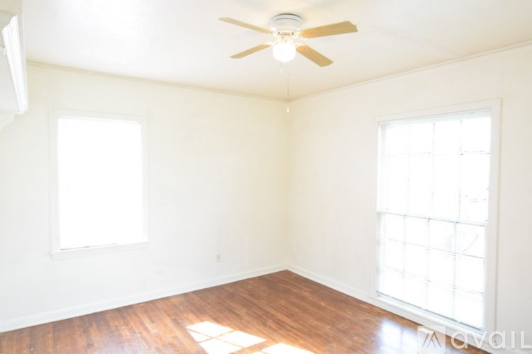 A room with a ceiling fan and two windows.