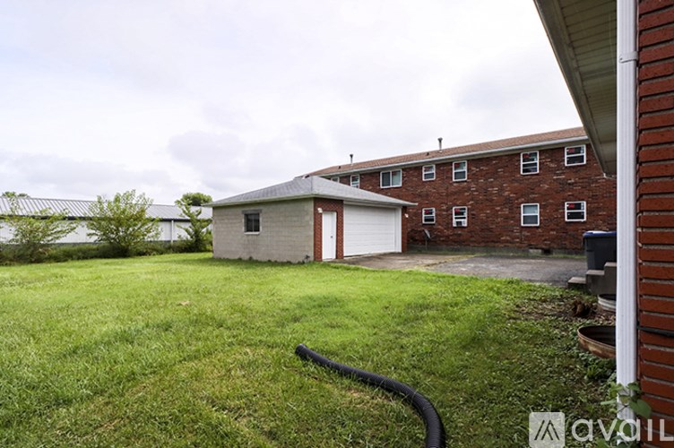 A house with a red door and a garage is surrounded by a grassy yard.