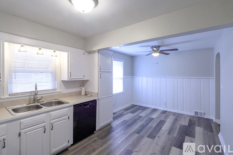 A kitchen with white cabinets and a wooden floor.
