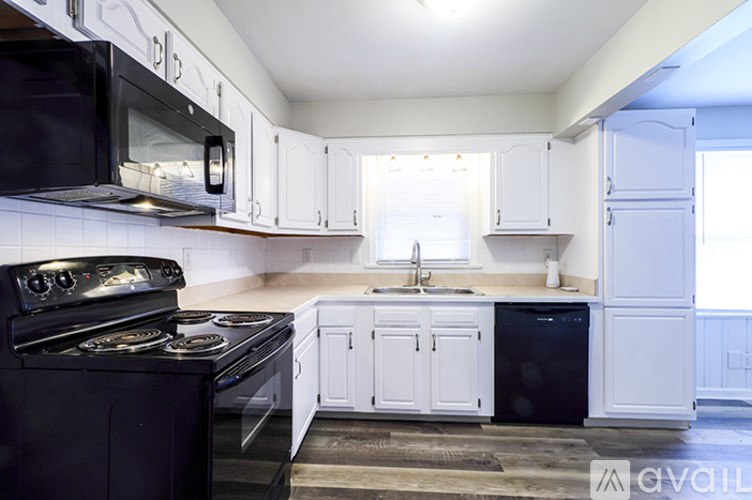 A kitchen with black appliances and white cabinets.