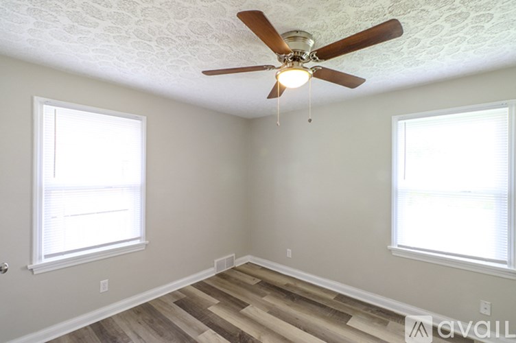 A room with a ceiling fan and two windows.