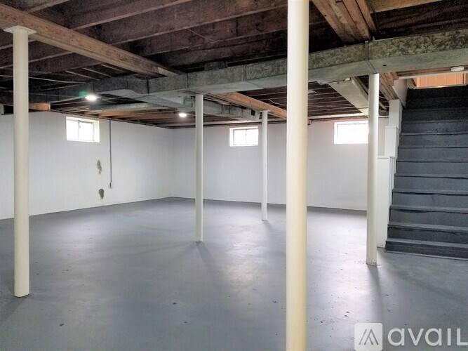 A spacious basement with a staircase on the right and a door on the left.