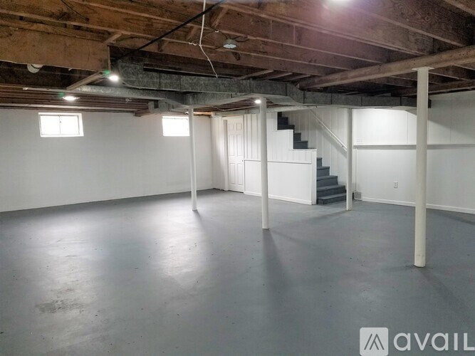 A spacious empty room with a staircase and wooden beams on the ceiling.