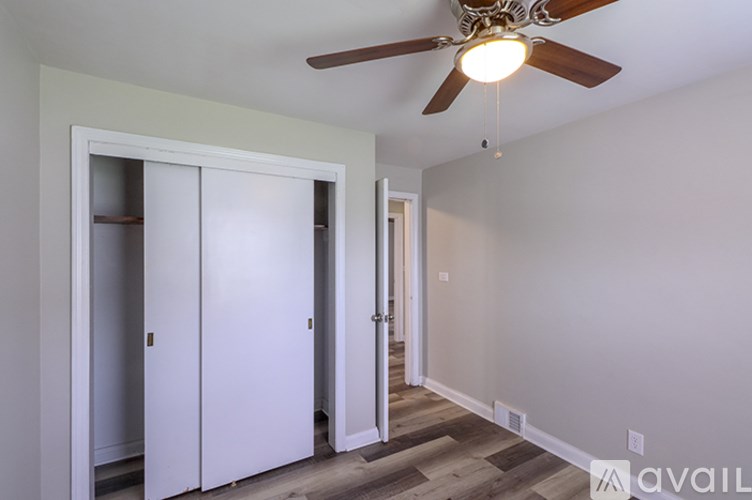 A room with a ceiling fan and a door leading to another room.