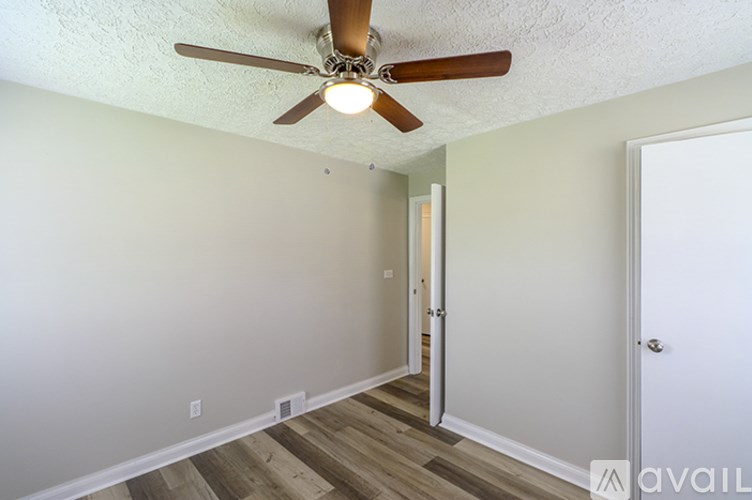 A room with a ceiling fan and wooden flooring.