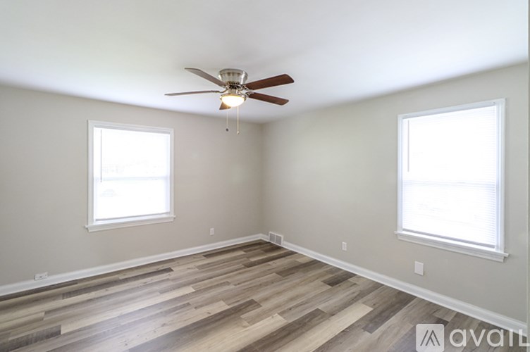 A room with a ceiling fan and two windows.