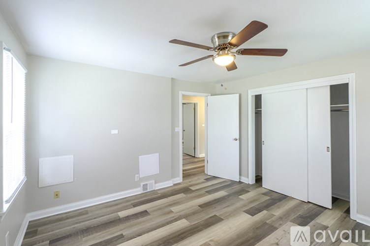 A room with a ceiling fan and wooden flooring.