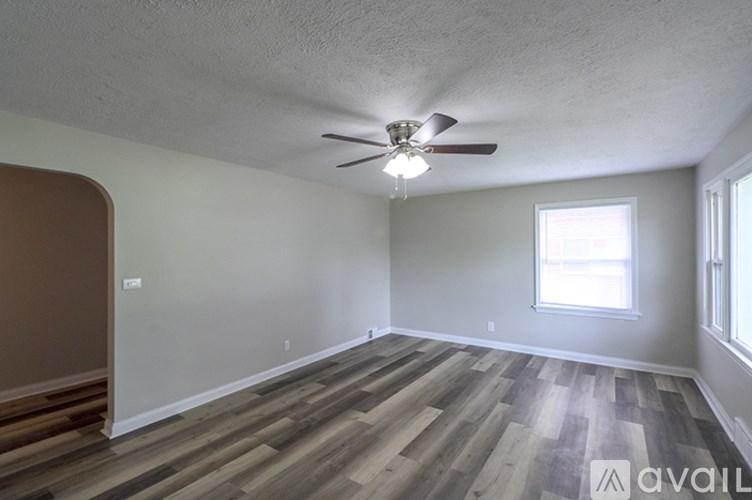A room with a ceiling fan and wooden flooring.