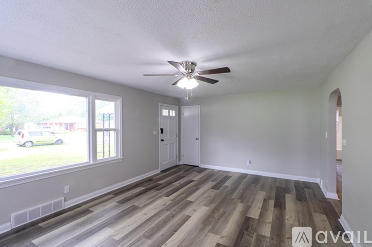 A room with a ceiling fan and wooden flooring.