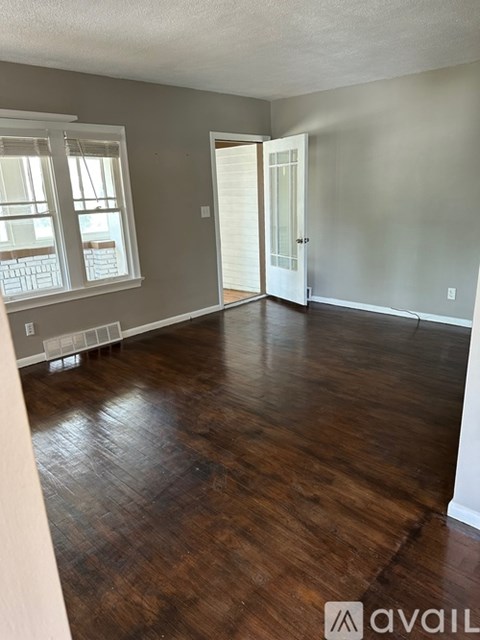 A room with wooden floors and a door leading to another room.