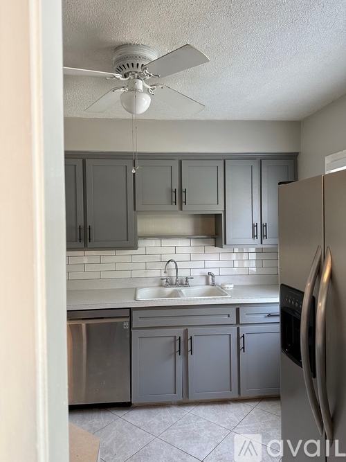 A kitchen with a stainless steel refrigerator and a fan on the ceiling.