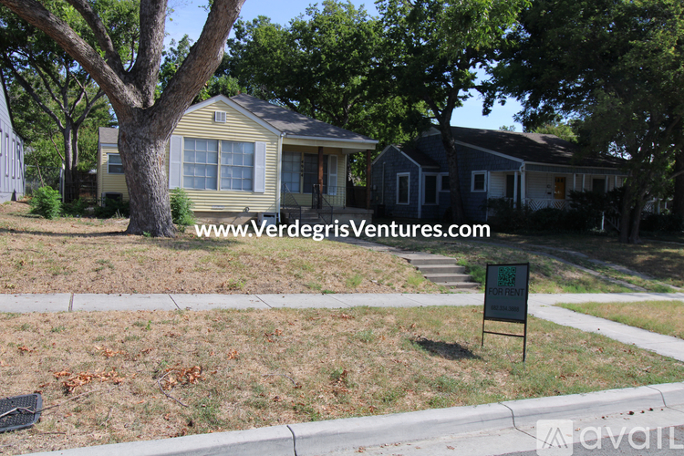 A house with a yard and a sign that says "For Sale".