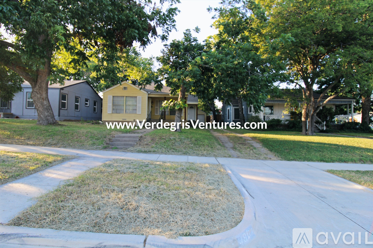 A residential area with houses and a grassy area in the foreground.