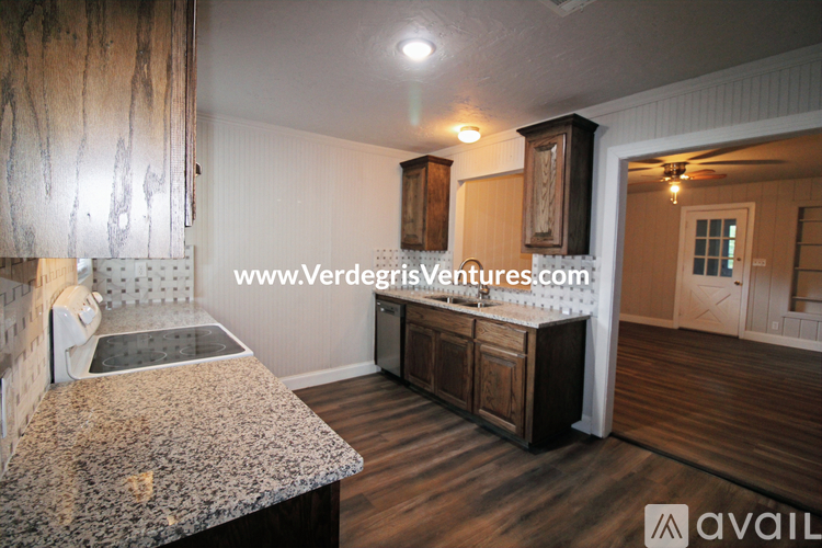 A kitchen with a granite countertop and wooden cabinets.