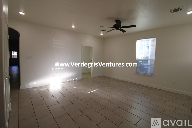 A room with a ceiling fan and a window with a view of a building outside.
