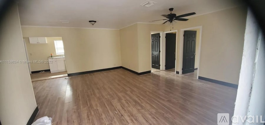 A spacious room with wood flooring and a ceiling fan.