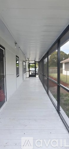 A long, narrow hallway with white walls and a white ceiling.