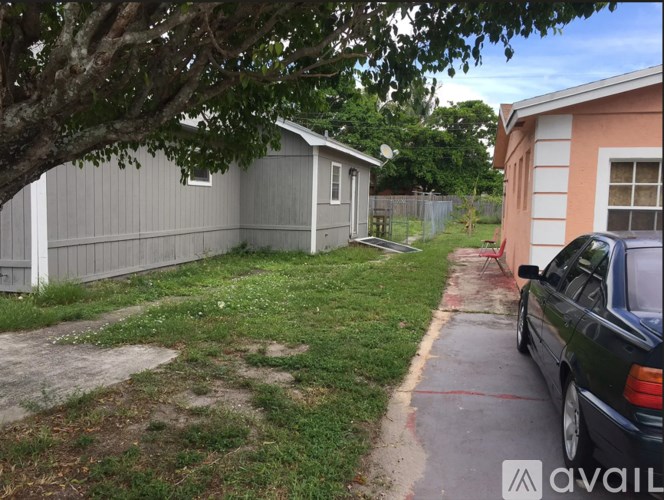 A black car is parked on a driveway in front of a house.
