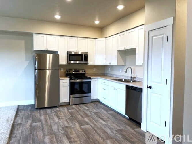 A kitchen with white cabinets and a stainless steel refrigerator.