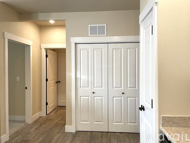 A white double door closet with a white door to the left and a white door to the right.