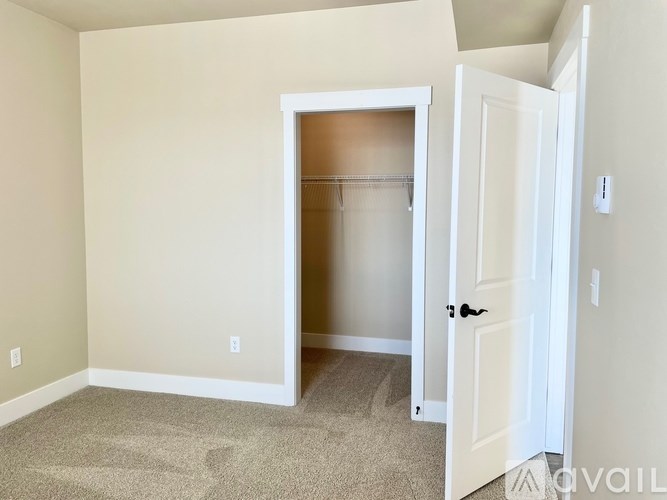 A room with a white door and a carpeted floor.