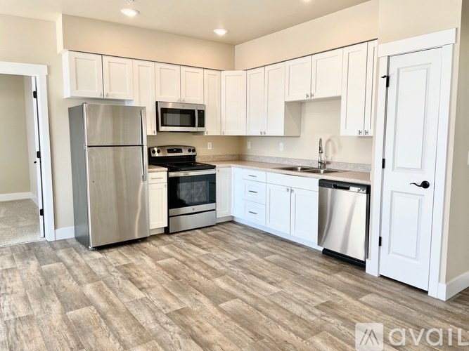 A kitchen with white cabinets and a wooden floor.