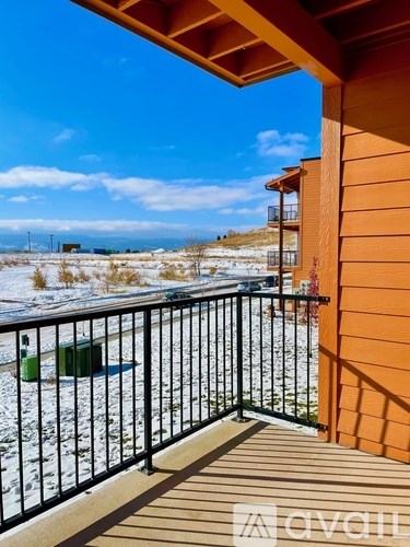 A balcony with a black railing and a green trash can.