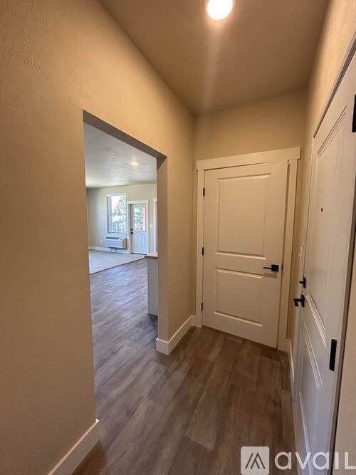 A hallway with a door on the right and a mirror on the left.