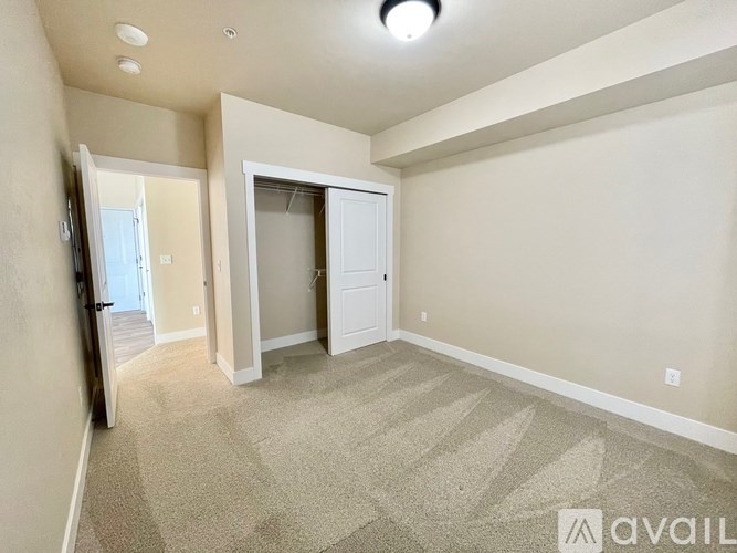 A carpeted room with a doorway leading to another room.