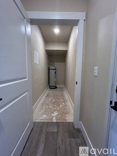A hallway with a white door and a white wall.