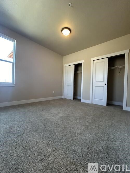 A room with carpeted floor and two doors.