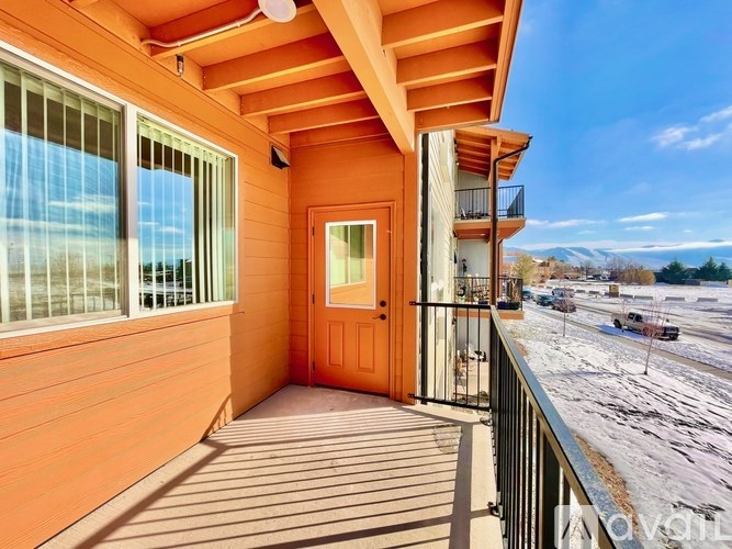 A balcony with a black railing and a brown door.